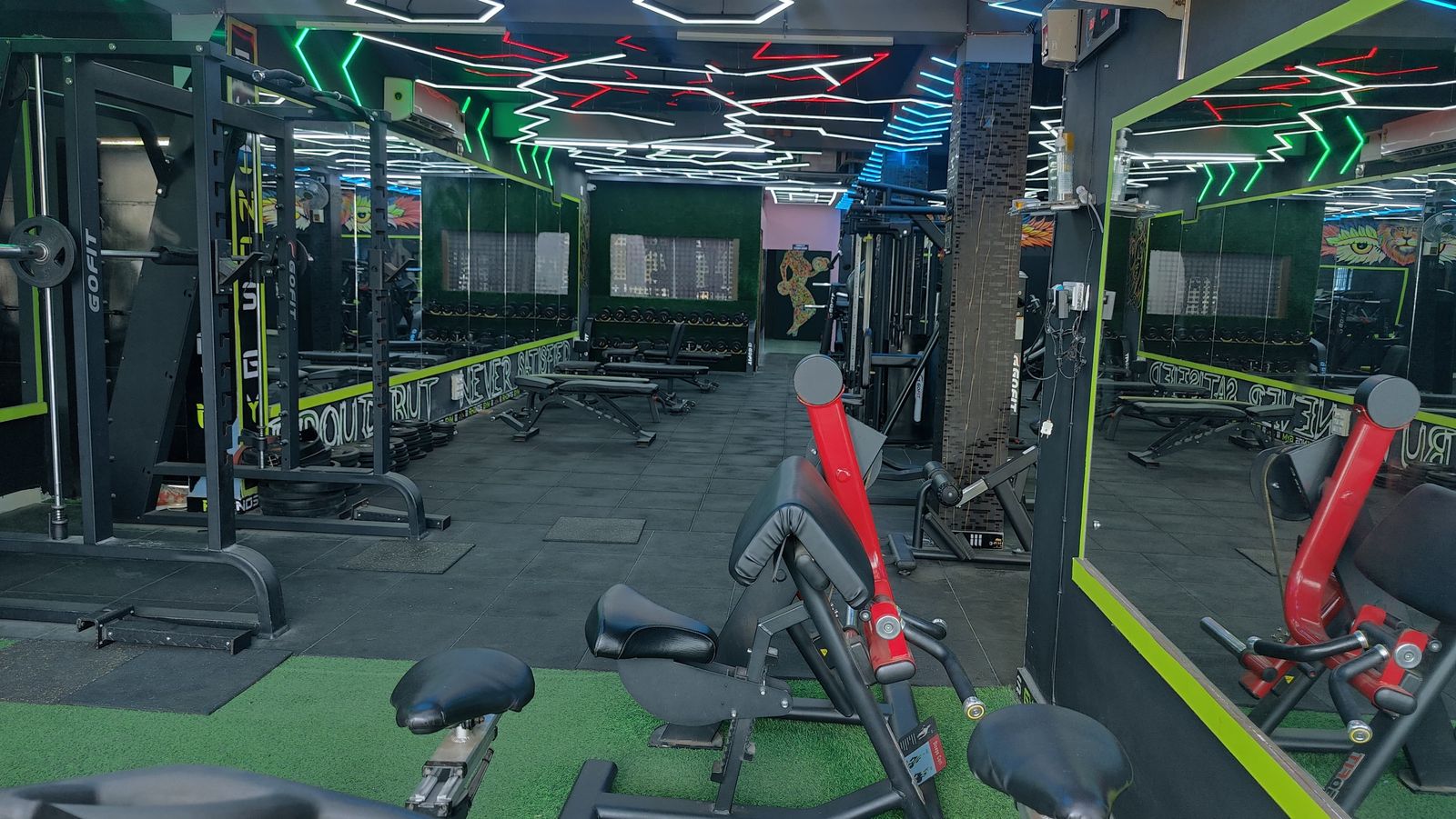 Rhinos Gym interior with machines, turf and neon ceiling lighting